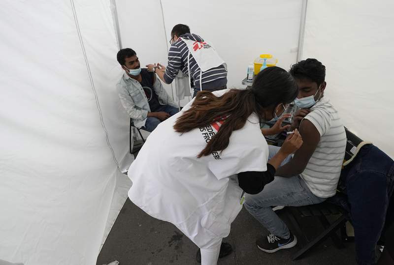 Aid group vaccinates migrants as France expands virus pass